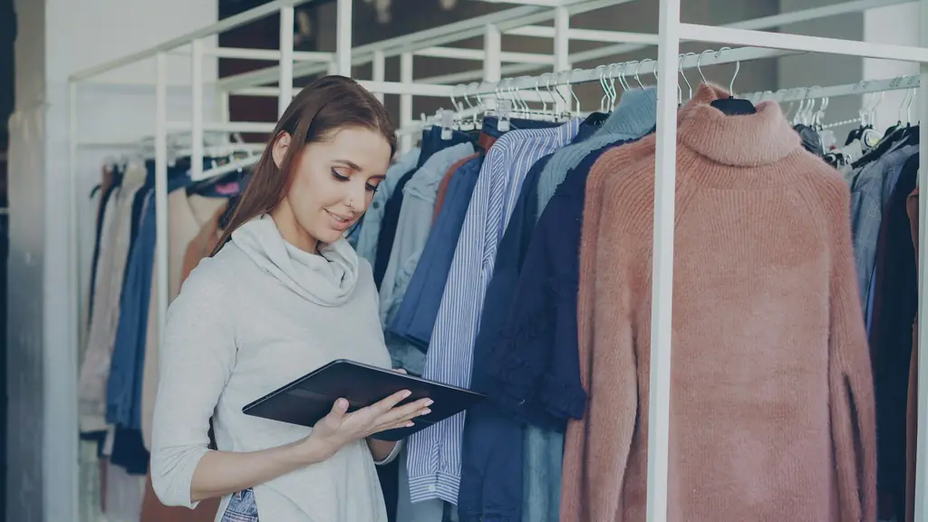 A boutique owner checking stock on a tablet between clothing racks